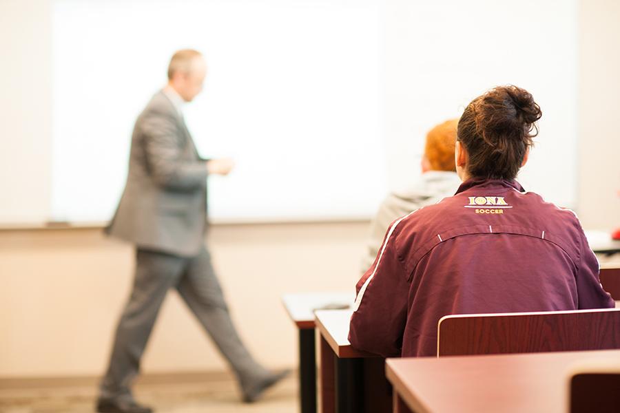 A professor in the background walks in front of his white board and a student wears her Ion soccer jacker.