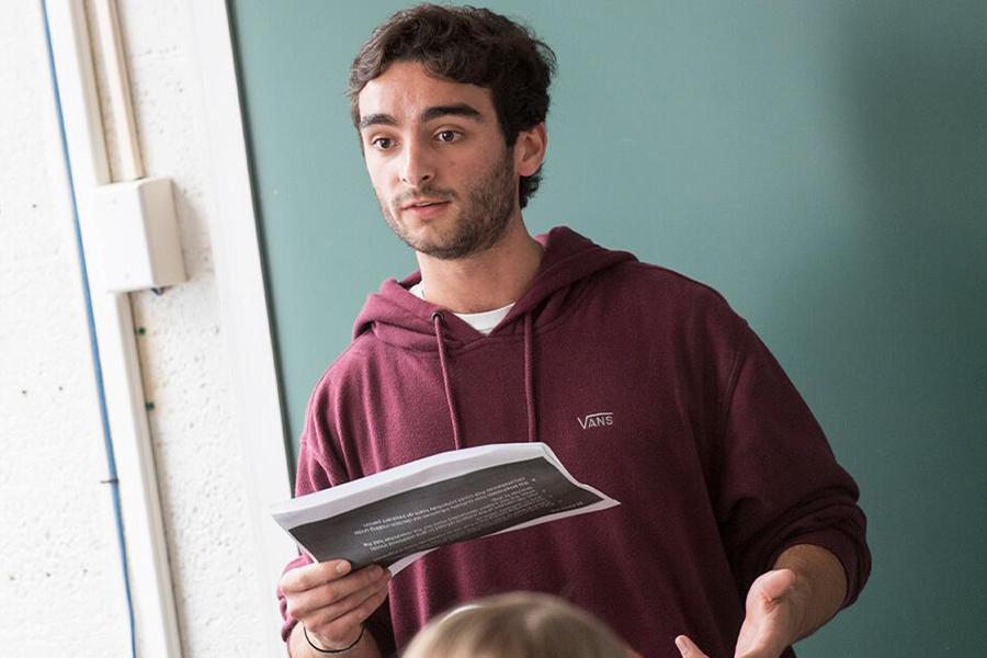 A criminal justice student stands in front of class and reads his report.