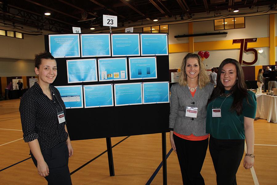 Three students stand near their poster made up of many blue papers at Iona Scholars Day 2015.
