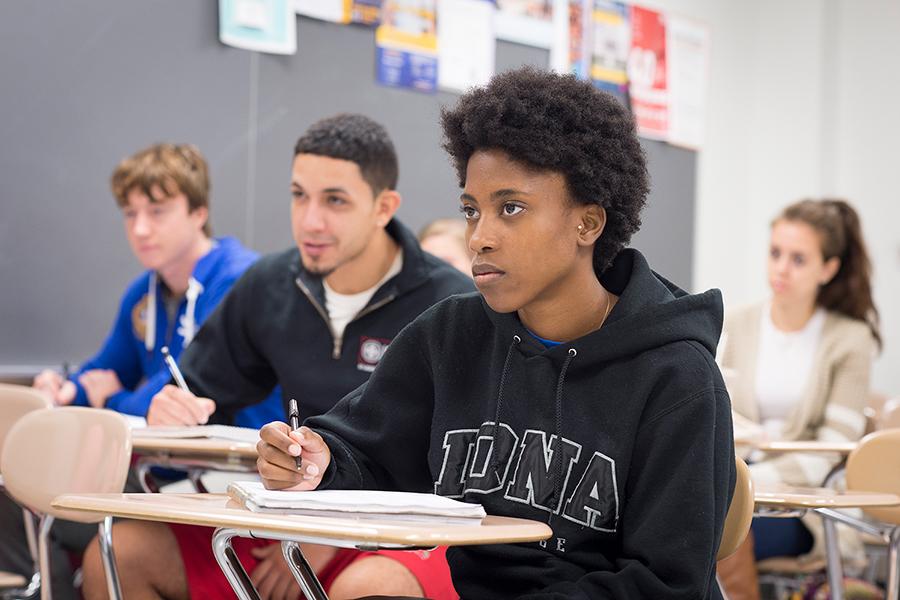 A female student takes notes in a class for her economics major.