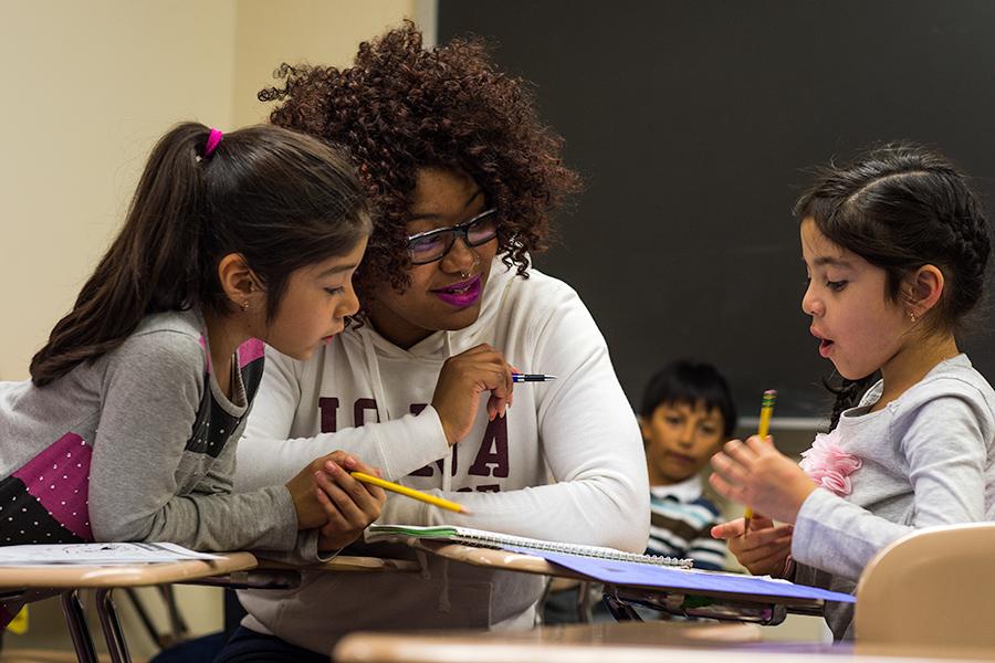 An education student tutors two young girls.