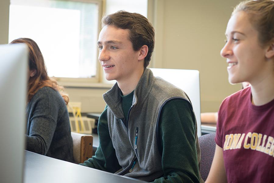 A group of students sit in front of a computer for their computer science class.