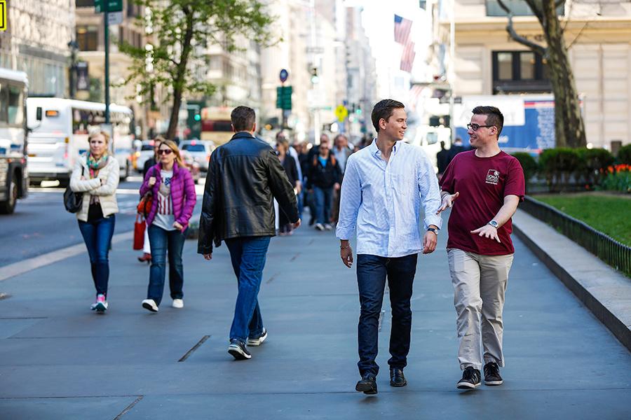 Two students walk down 42 street in Manhattan having a dynamic conversation.