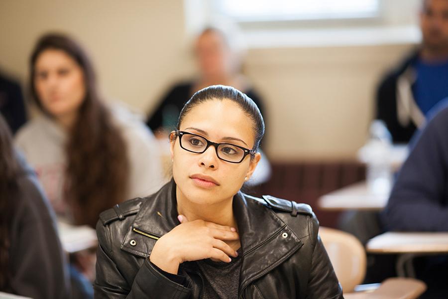 A student in a leather jacket pays close attention in class.