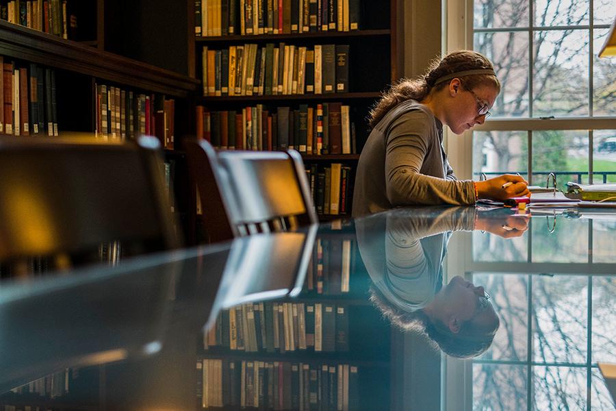 A female student studies by herself in the library.