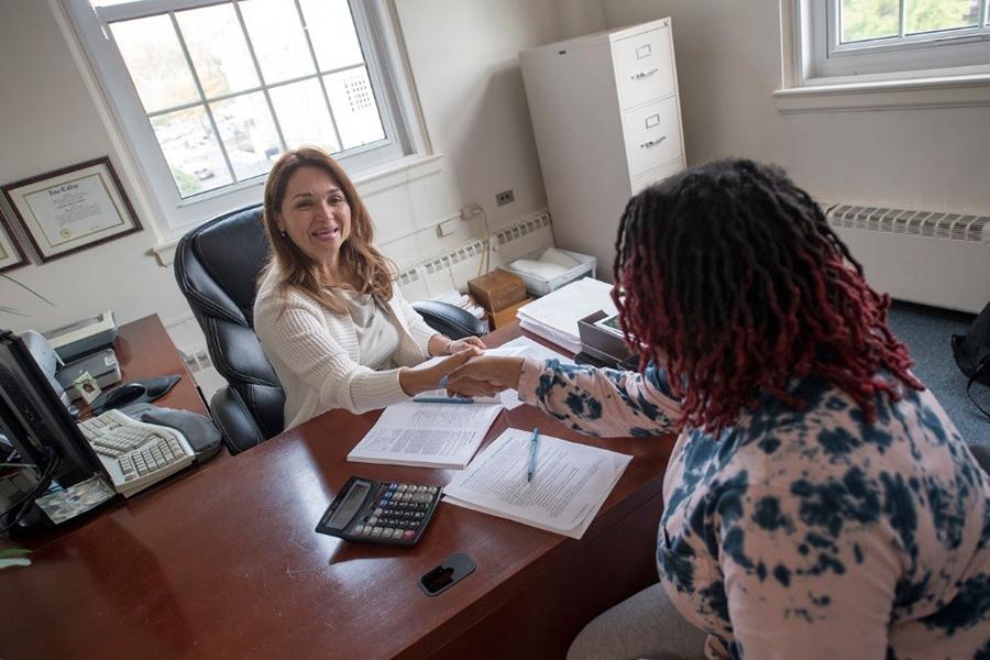 A student and a counselor shake hands after a meeting.