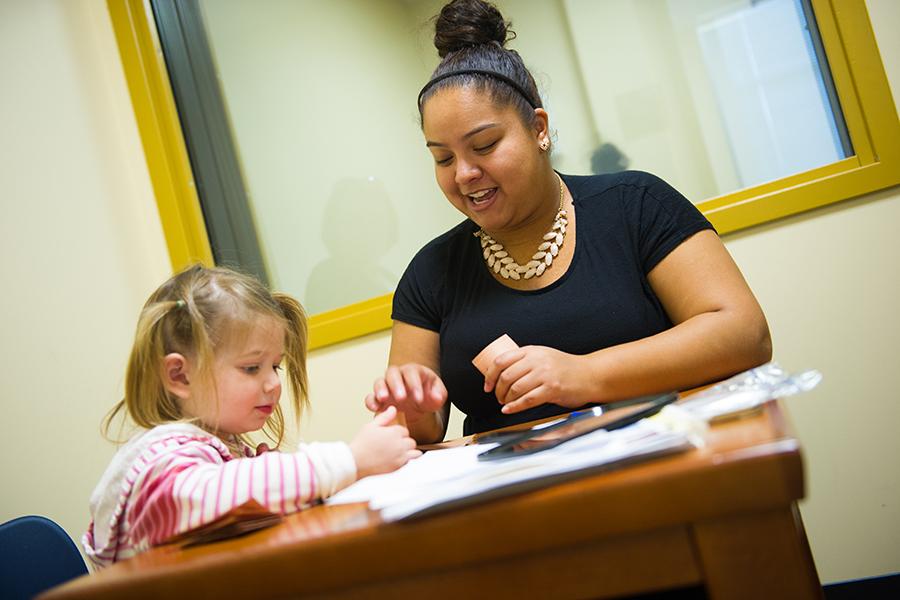 A speech pathology student works with a young girl by using cards.