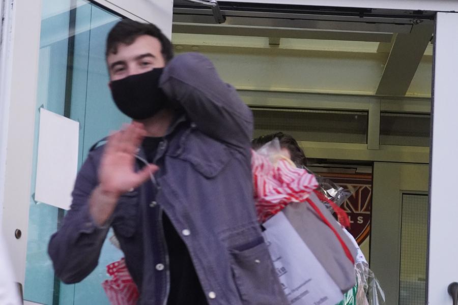 A student waves as he carries a Thanksgiving basket to the van.