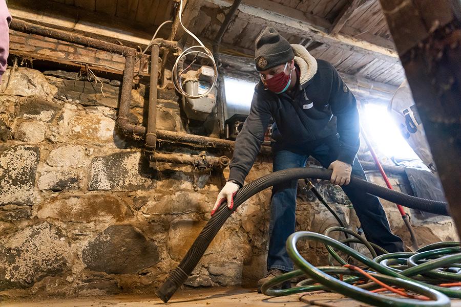 A student vacuums the basement at the Fuller House in Yonkers.