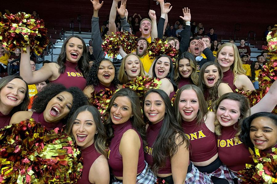 The Iona college dance team and cheerleaders smile and raise their pom-poms.