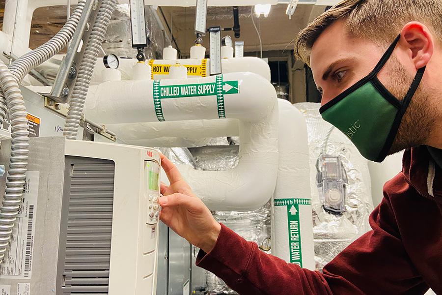 Thomas Van Wert, the Cenergistic energy specialist embedded with Iona University, adjusts the variable frequency drive (VFD) on a supply fan at the LaPenta School of Business.