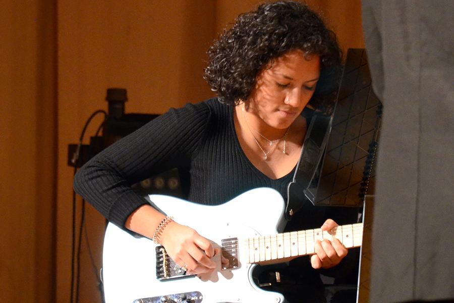 A student plays guitar in the band.