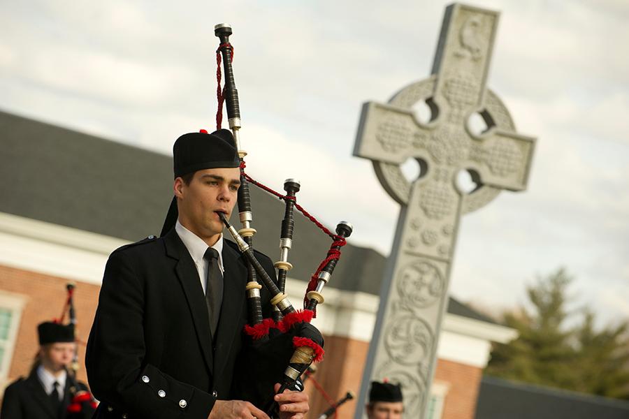 A piper plays next to the Celtic cross on East Hill.