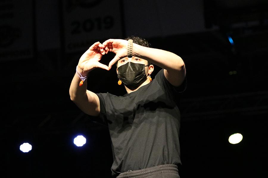 A student makes a heart symbol with his hands at the fashion show.