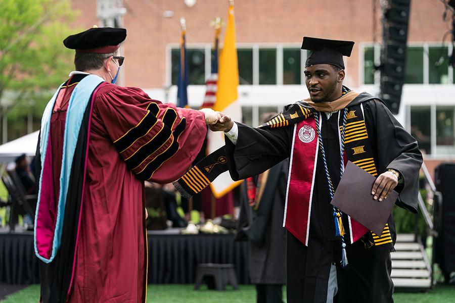 A student celebrates with a fist bump with Carl at the 2021 in-person recognition ceremony.