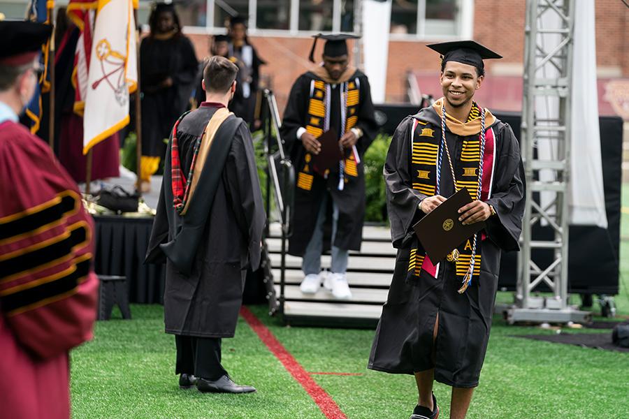 Iona student Matt walks with his diploma at the in-person recognition ceremony.