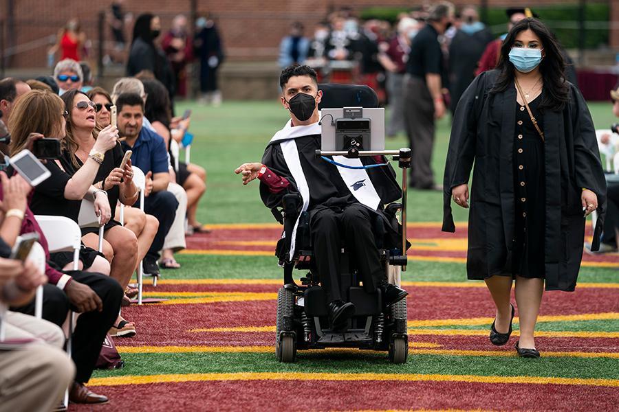 A graduate in a motorized chair in the procession at the 2021 in-person recognition ceremony.