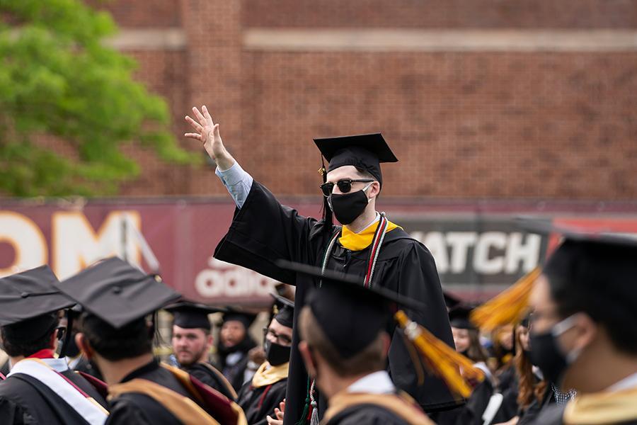 A student raises his hand at the 2021 in-person recognition ceremony.