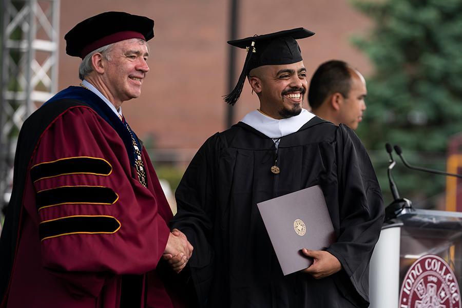 A graduate shakes hands with President Carey at the 2021 in-person recognition ceremony.