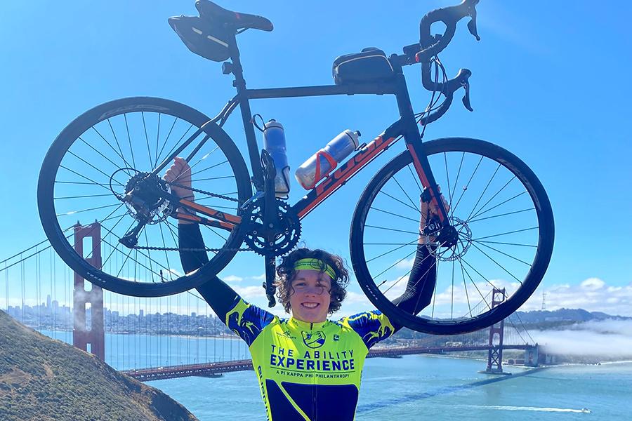 Aidan Connolly raises his bike overhead at the Golden Gate Bridge.