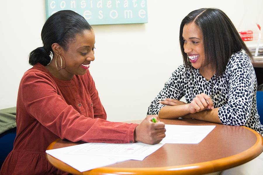 A mentor and her student review coursework and smile.