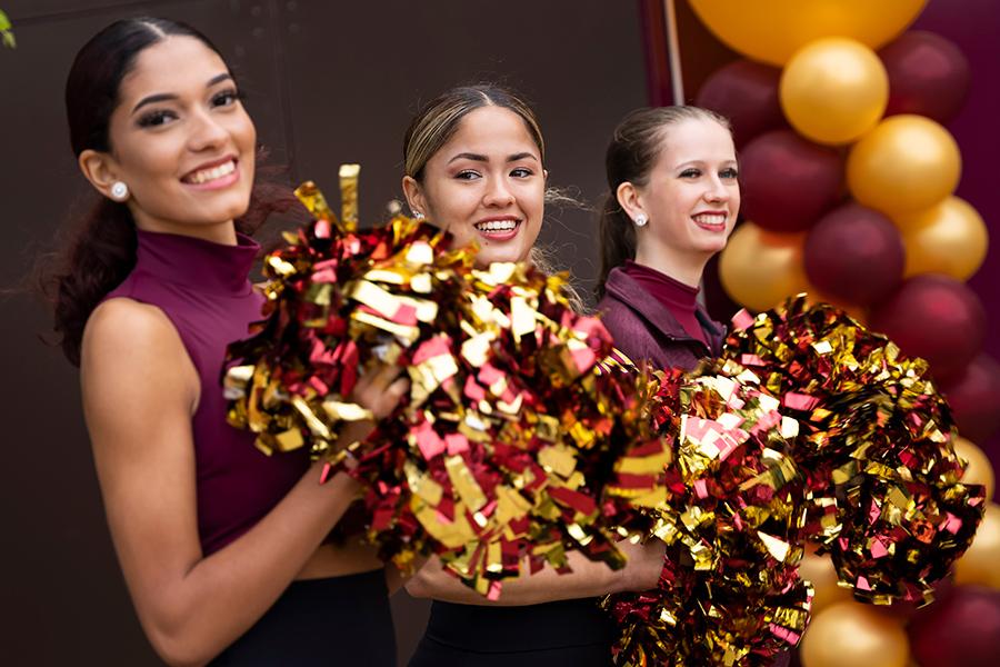 Three members of the dance team smile.