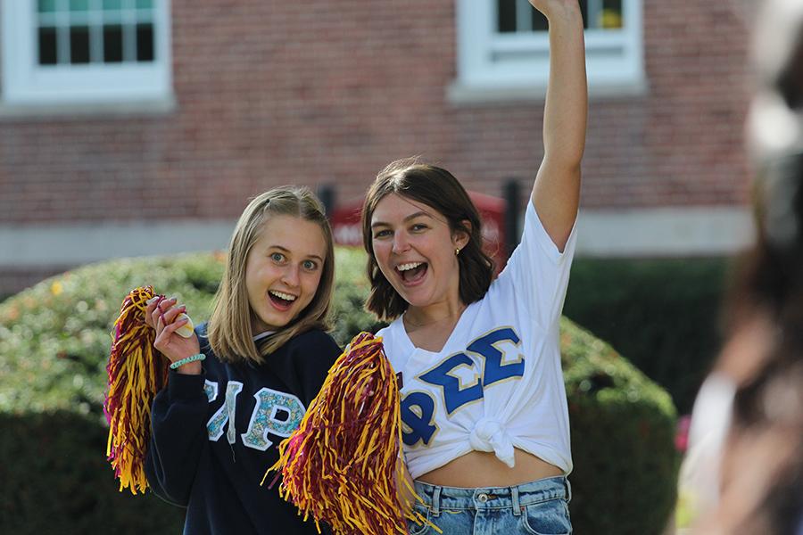 Two sorority students smile and wave pom-poms.