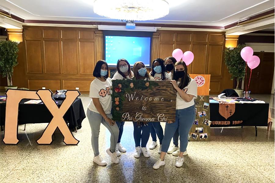 Phi Gamma Chi hold a welcome sign in the Burke Lounge.