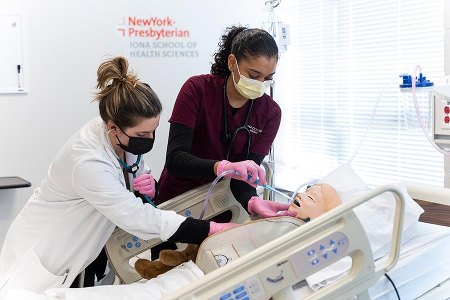 Nursing students practice using an air tube on a patient.
