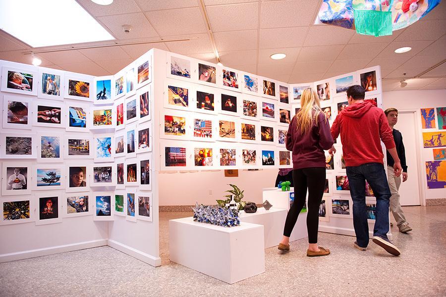 Three students walk through the art gallery and enjoy the paintings.