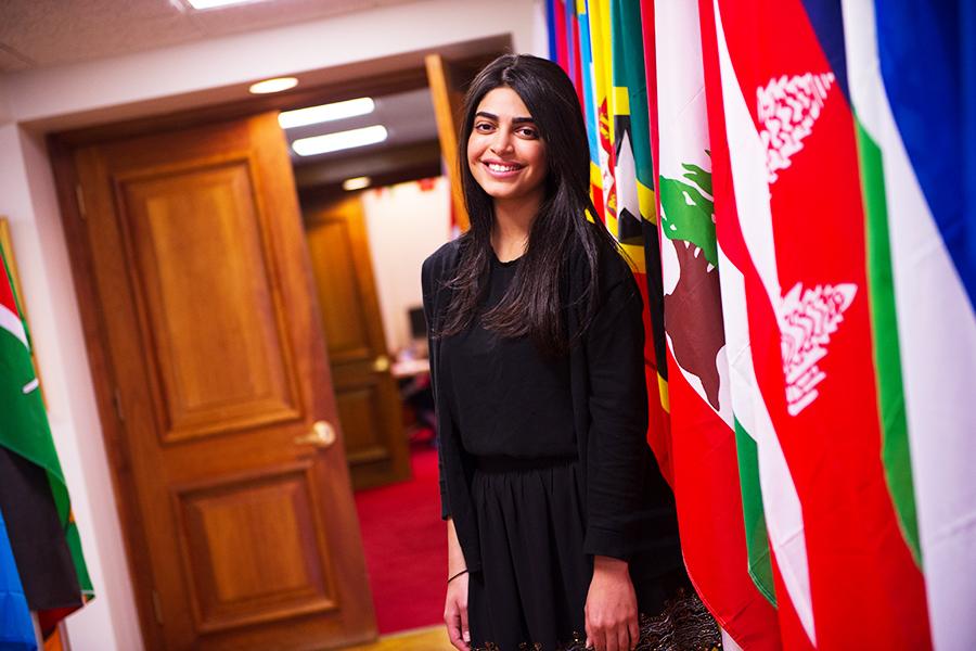 A student stands amidst a hallway of flags from around the world.