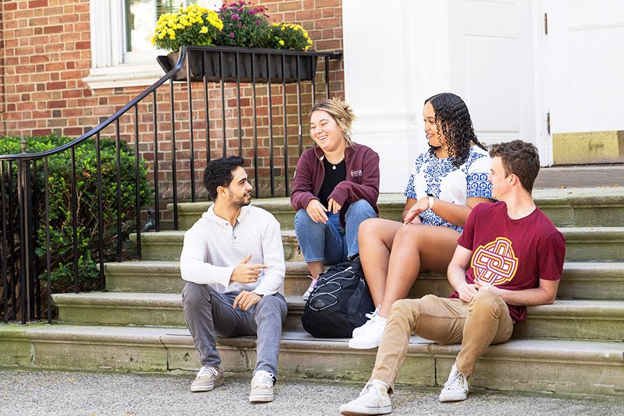 Four undergraduate students talk on the steps of the Advising office.