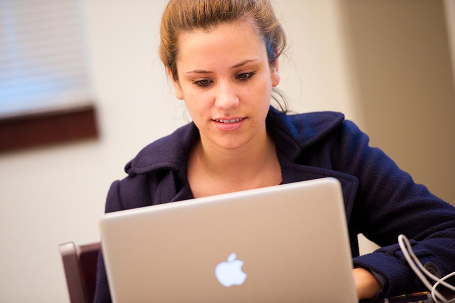 A female student works on her mac laptop in the library.