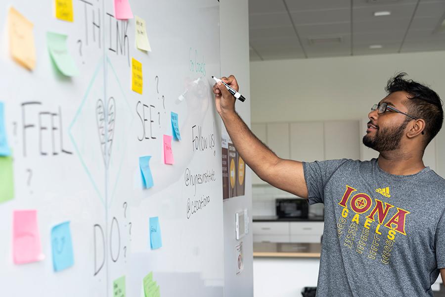 A student writes on a white board in the Hynes Institute.