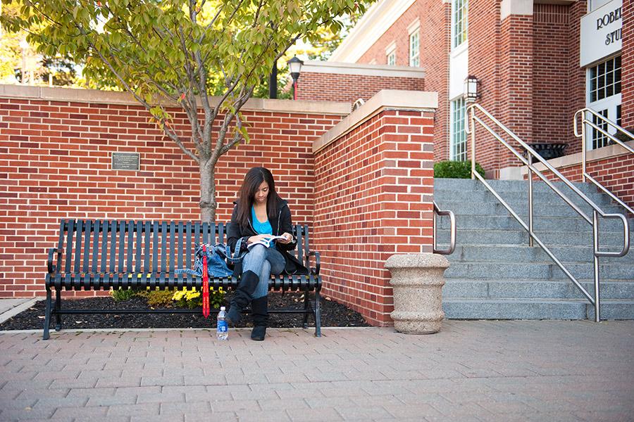 A student reads a book outside of the LaPenta School of Business.