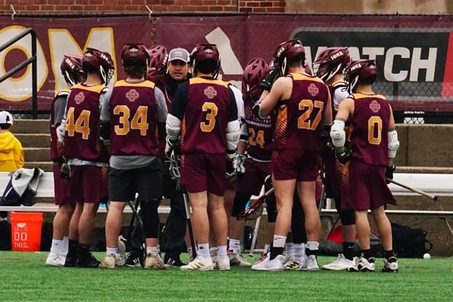 The Iona men's lacrosse club team huddle on field with their coach during a game.