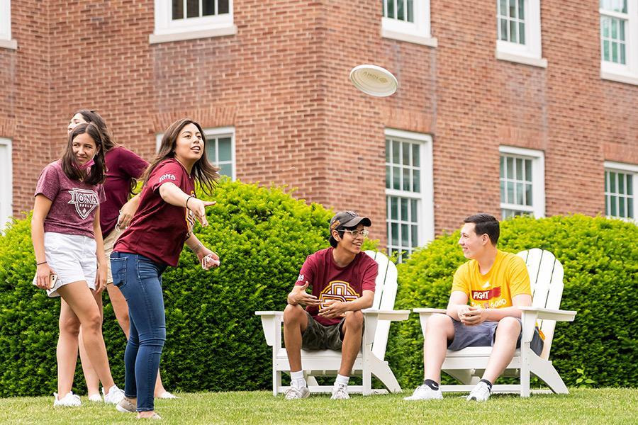 Students play frisbee on the lawn of McSpedon Hall.