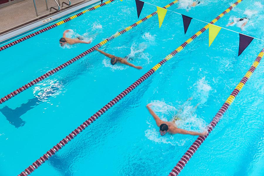 Three swimmers race in the Hynes Pool.