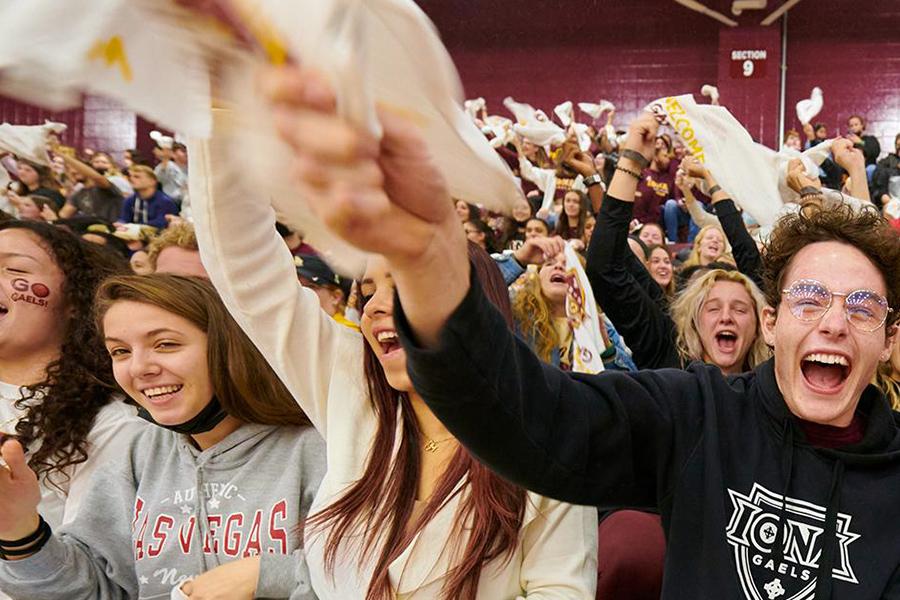 Students wave towels at a basketball game.