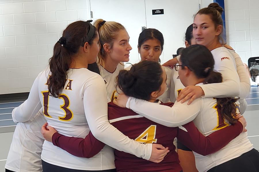The women's club volleyball team huddles up.