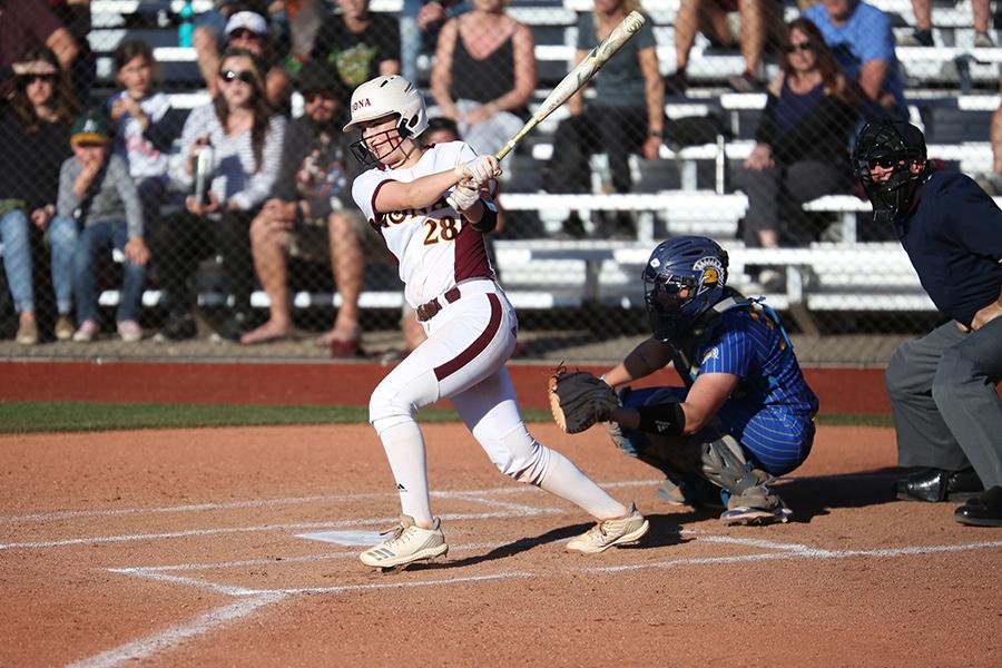 A member of women's softball swinging at a pitch.