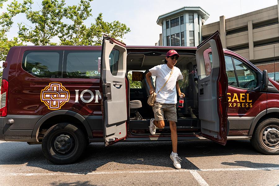 A student steps out of the Gael Express shuttle at the New Rochelle train station.