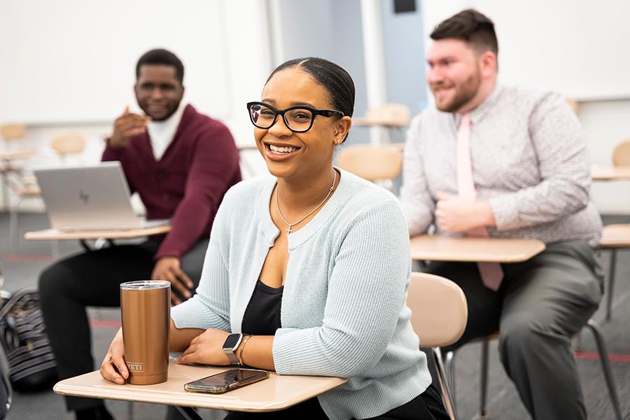 Three graduate students in a class smiling.