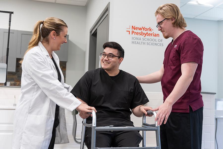 Two OT students and a professor work on assisting a client with a walker.