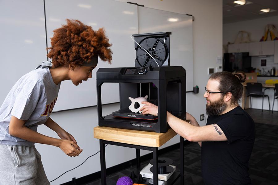 Rob and a student work with the 3D printer.