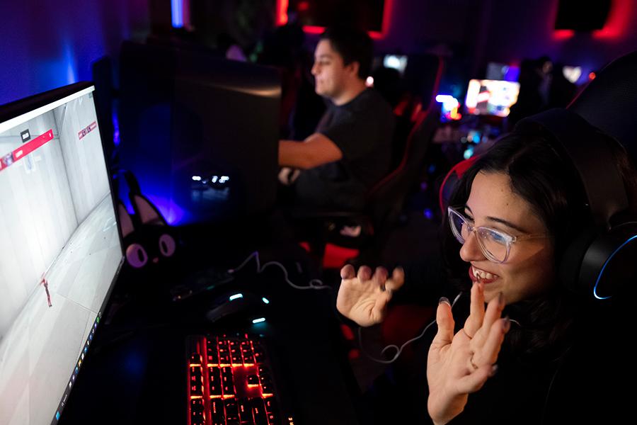 An esports player smiles and raises her hands in victory.