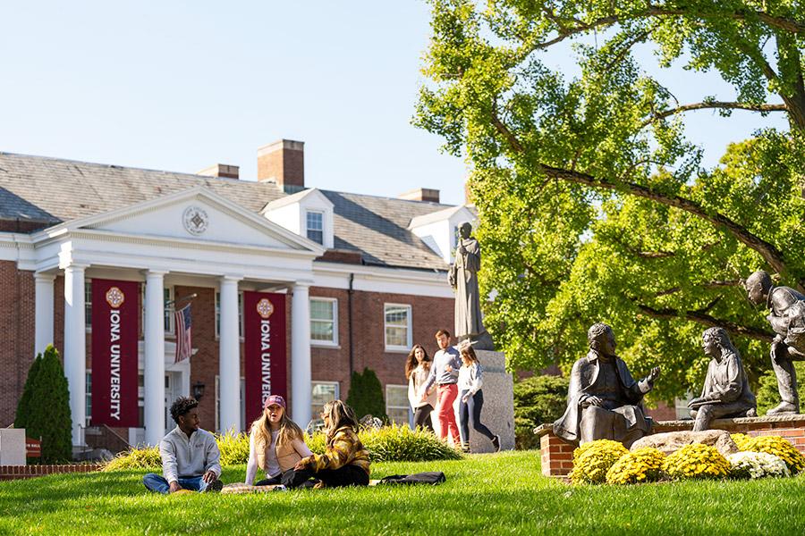 Students sit in the sun outside of McSpedon Hall and chat.