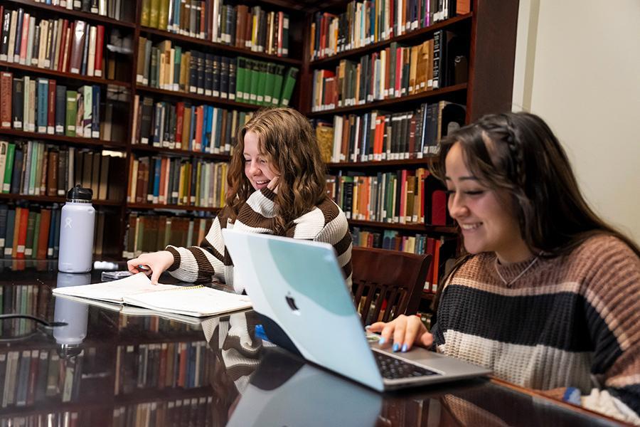 Two students study and smile in Ryan Library.