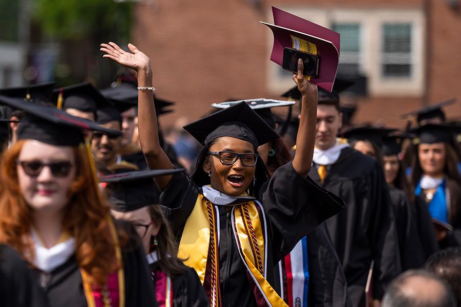 A 2023 graduate raises her arms in celebration.