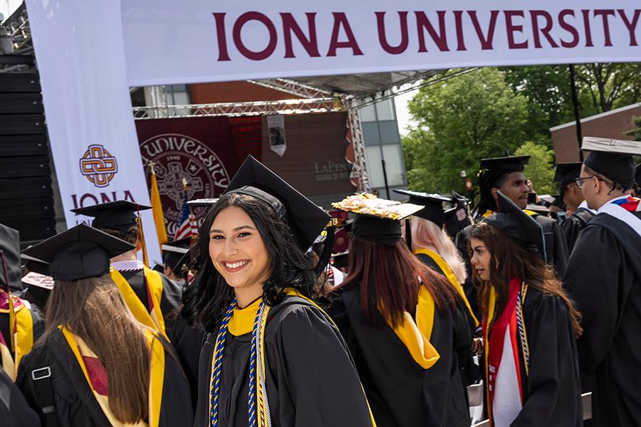 A graduate in front of the stage smiles.